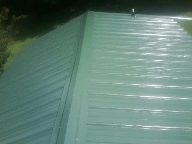 New green metal panels meeting at the ridge of a roof — Flat Roof Repair work by our crew in Wrightsboro