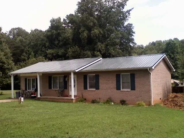Gray metal roof on a brick ranch house with a side carport in Wrightsboro