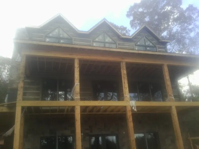 Dormers and porch framing on a large log home under construction — Roof Coating work by our crew in Wrightsboro