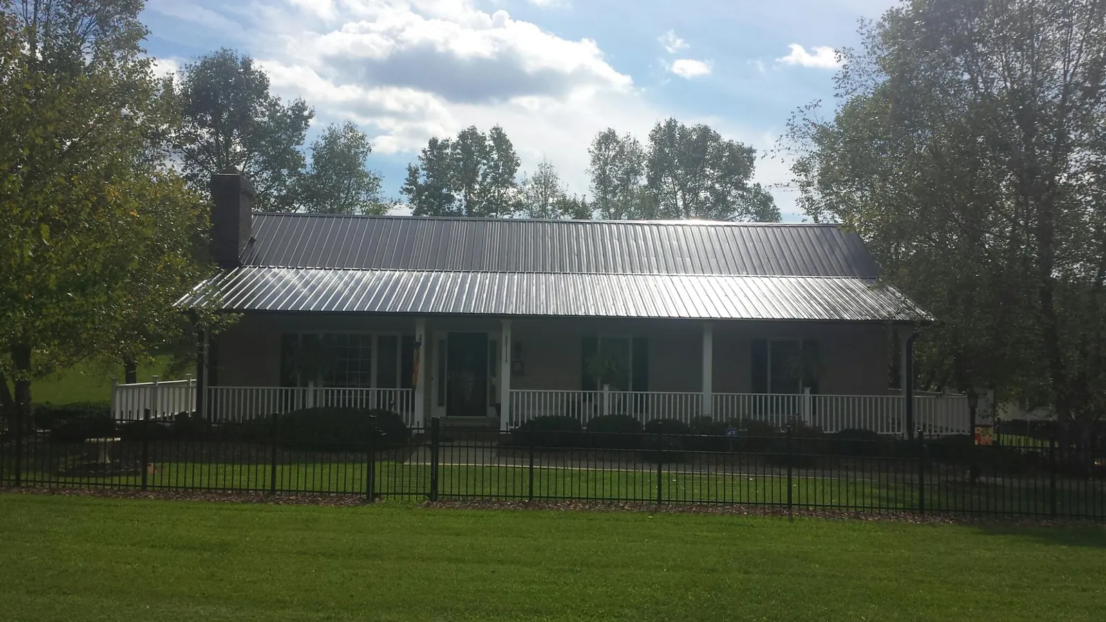 Gray metal roof on a brick ranch with a full width front porch — Gutter Guard Installation work by our crew in Wrightsboro