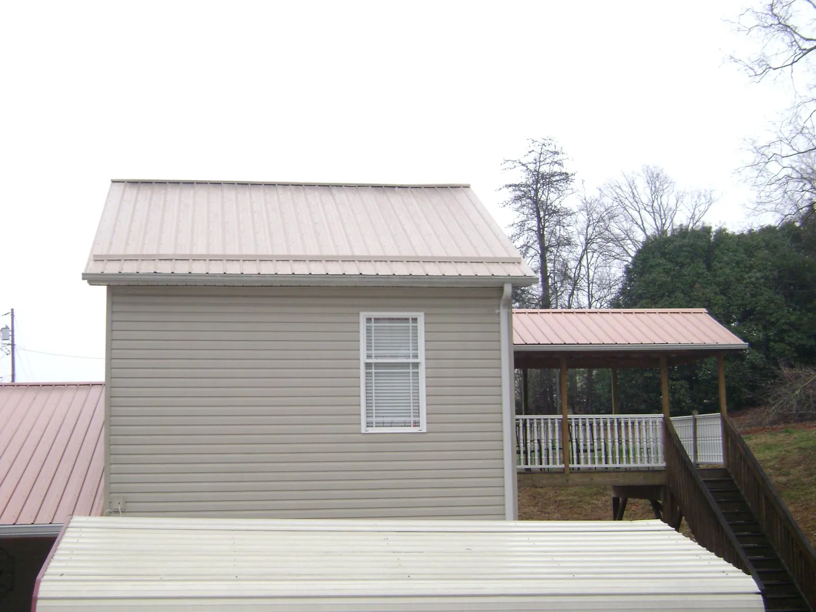 Tan metal roofs on a two story addition and attached porch, from a Roof Replacement job in Wrightsboro