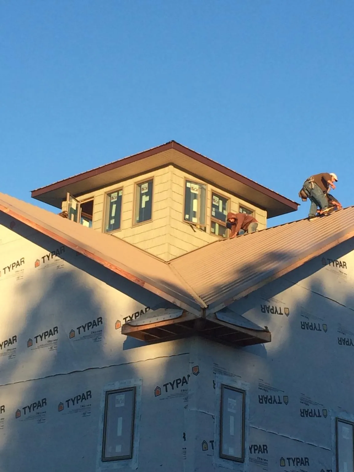 Roofers working around a rooftop cupola on a new metal roof at sunset — Roof Waterproofing in Wrightsboro by Roofing Brothers